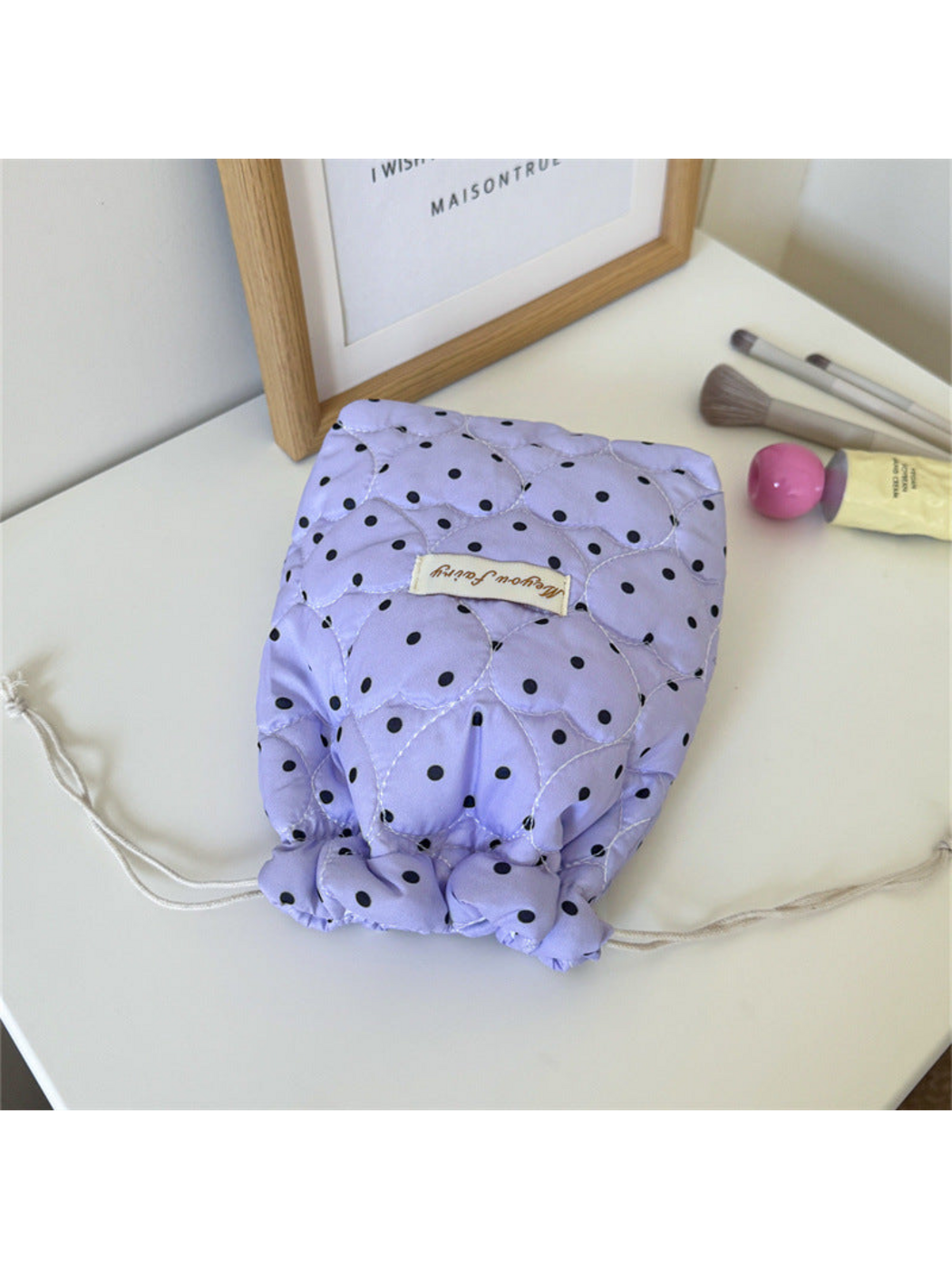 Purple cosmetic pouch with black polka dots and heart-shaped quilting on a tabletop