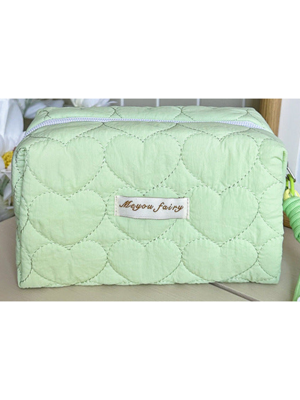 Mint heart-quilted pouch body with white zipper and sewn label; limited detail view