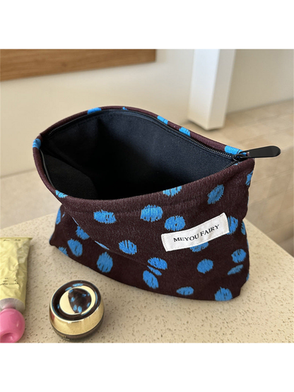 Brown cosmetic bag with blue dots, open to show the black interior