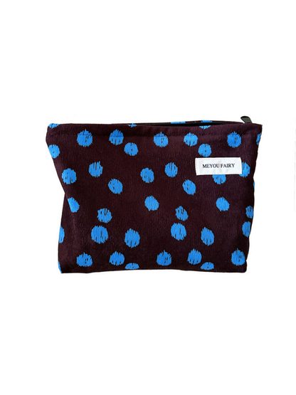 Brown cosmetic bag with irregular blue dots and a white label, front view