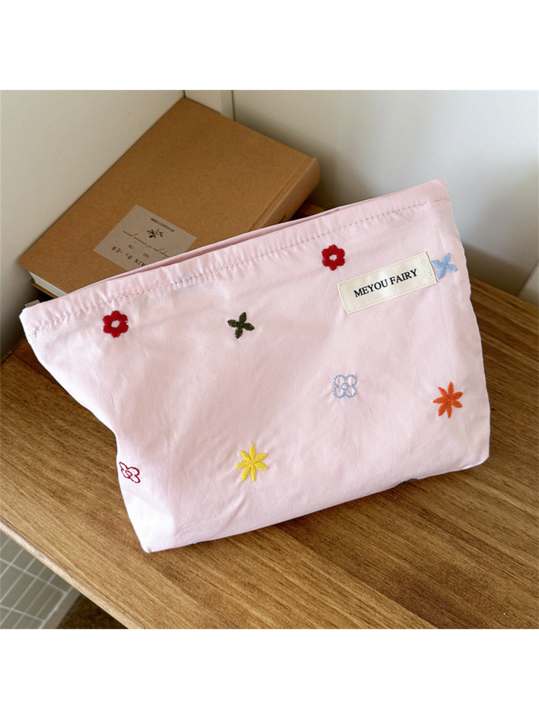 Pink makeup bag with scattered multicolored embroidered flowers, front view