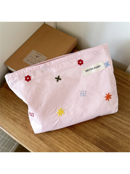 Pink makeup bag with scattered multicolored embroidered flowers, front view