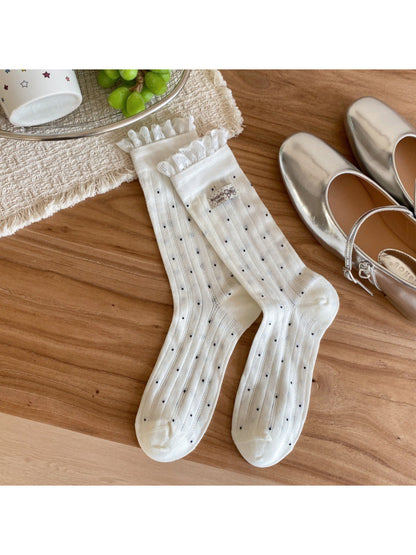 Model wearing soft ribbed beige socks with black polka dots