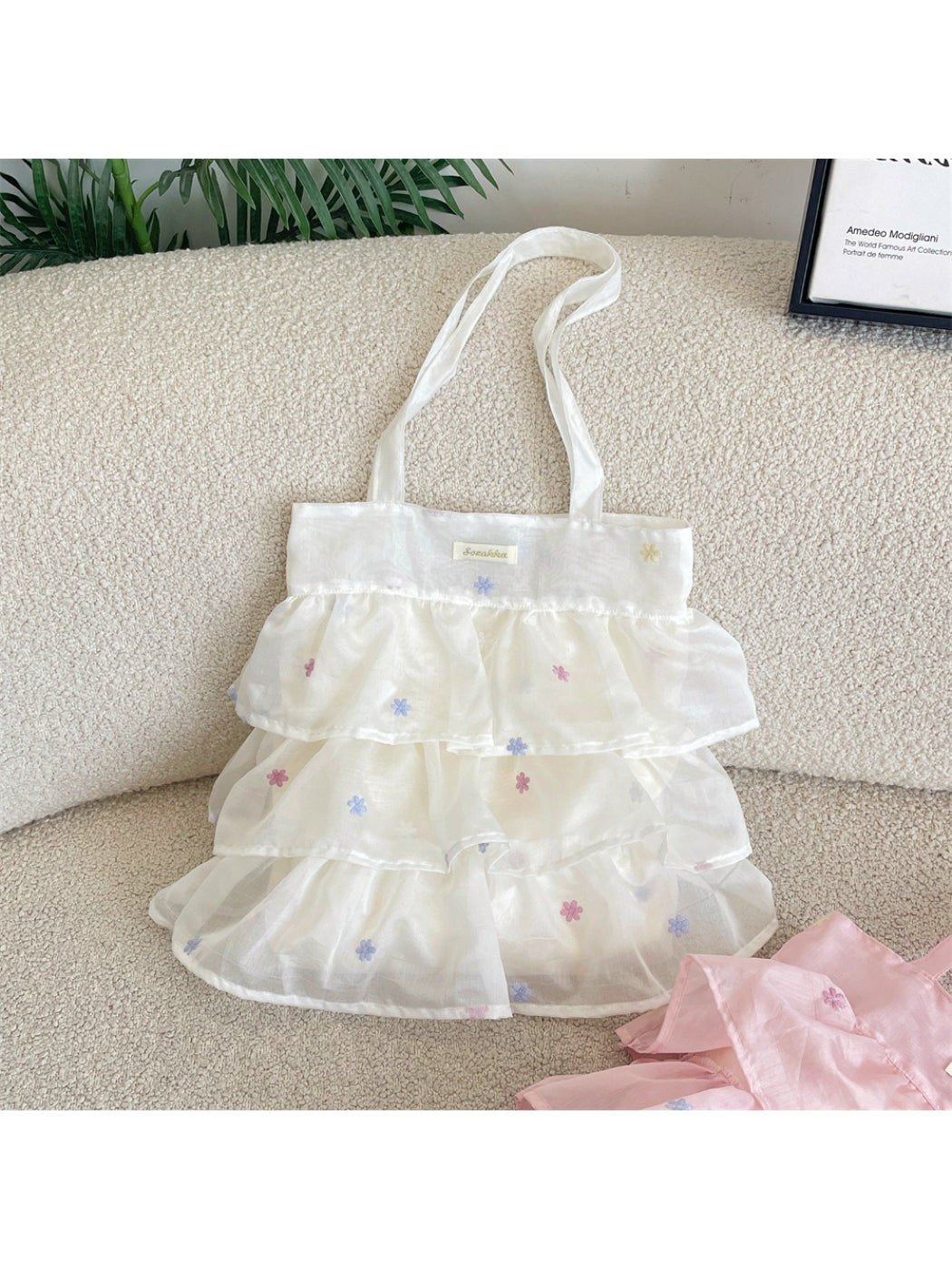 Cosbai tote bag held by hand, displaying size and pastel mesh texture