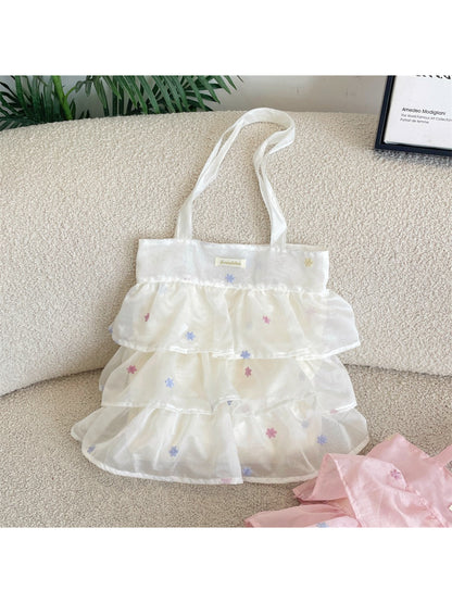 Cosbai tote bag held by hand, displaying size and pastel mesh texture