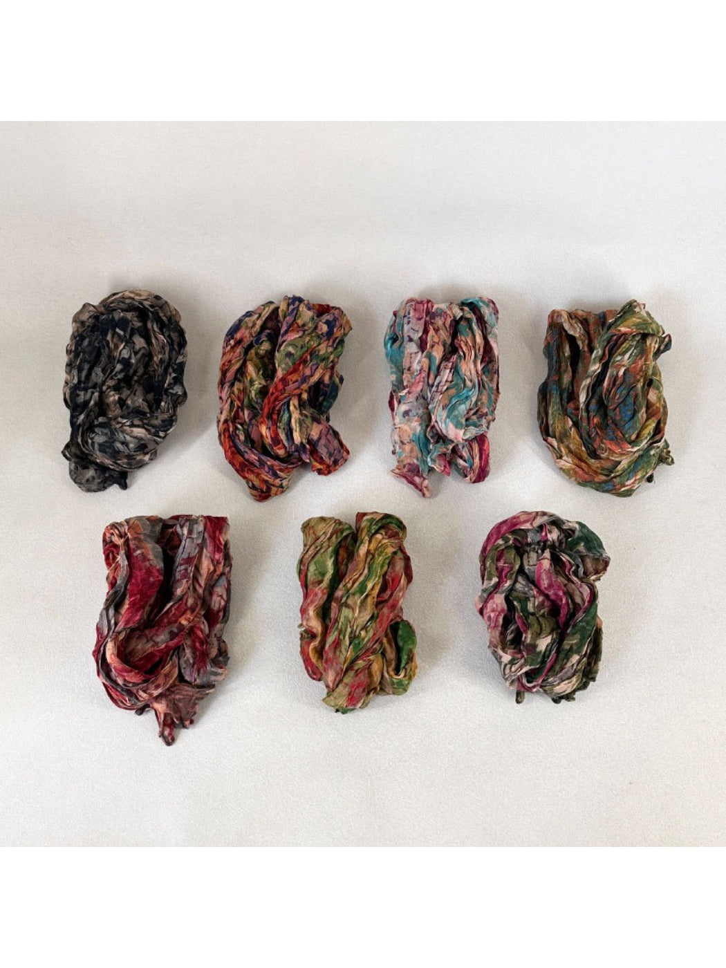Scarvii scarf displayed on a wooden surface emphasizing the artistic textured print
