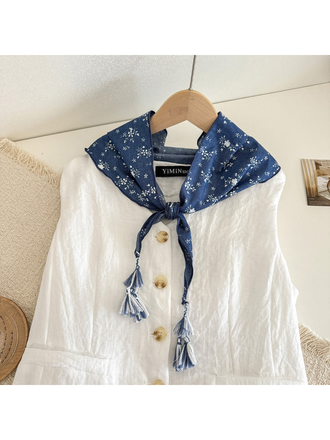 Close-up of blue floral print and tassel detail on triangle scarf