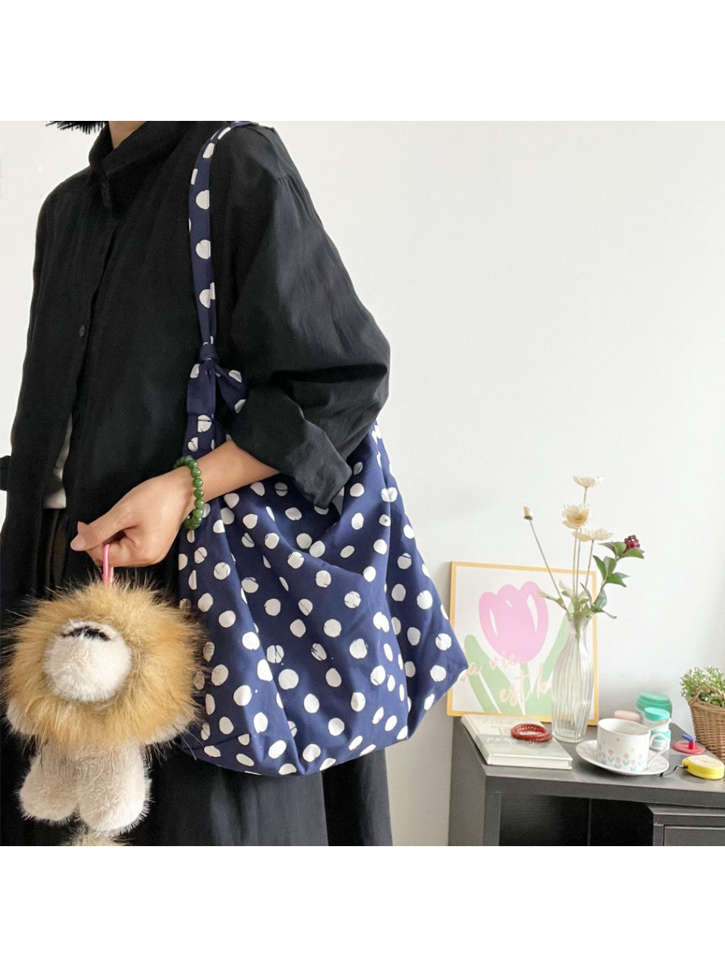 Close-up of gold lion charm attached to navy polka dot shoulder bag