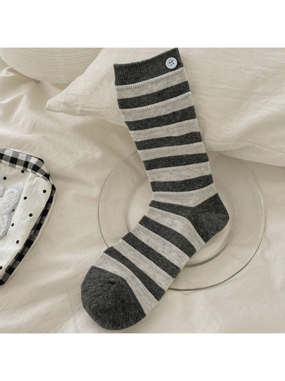 Rufia striped crew socks rolled up to showcase button design and fabric texture
