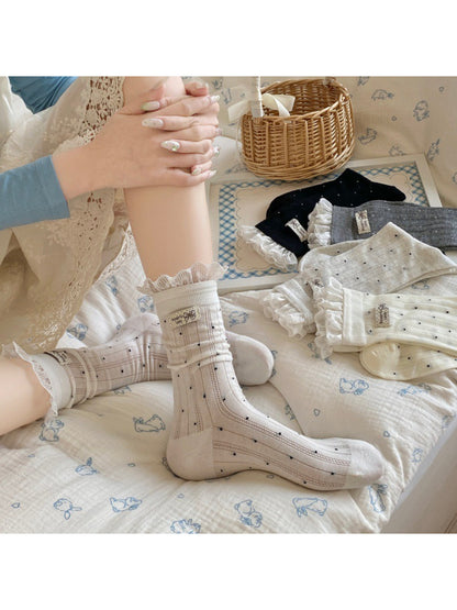 Pair of soft ribbed socks with black polka dots displayed on wooden surface