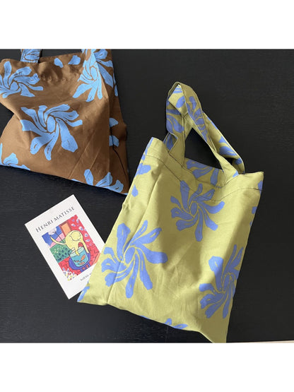 Cosbai reusable tote bag with abstract floral design placed on wooden surface