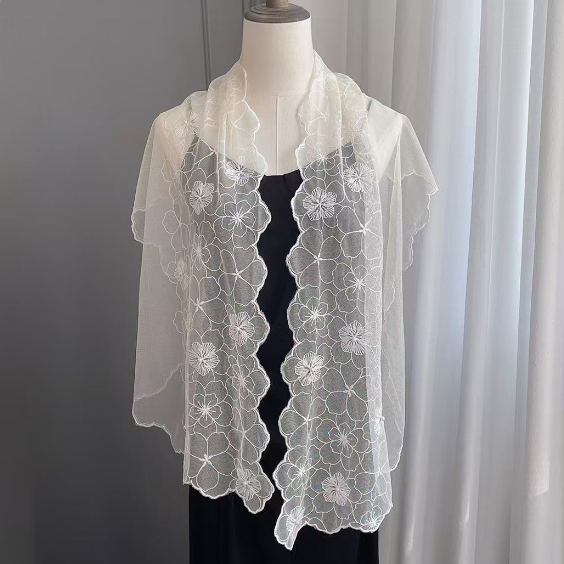 Folded floral lace scarf with delicate pearl trim on a white background