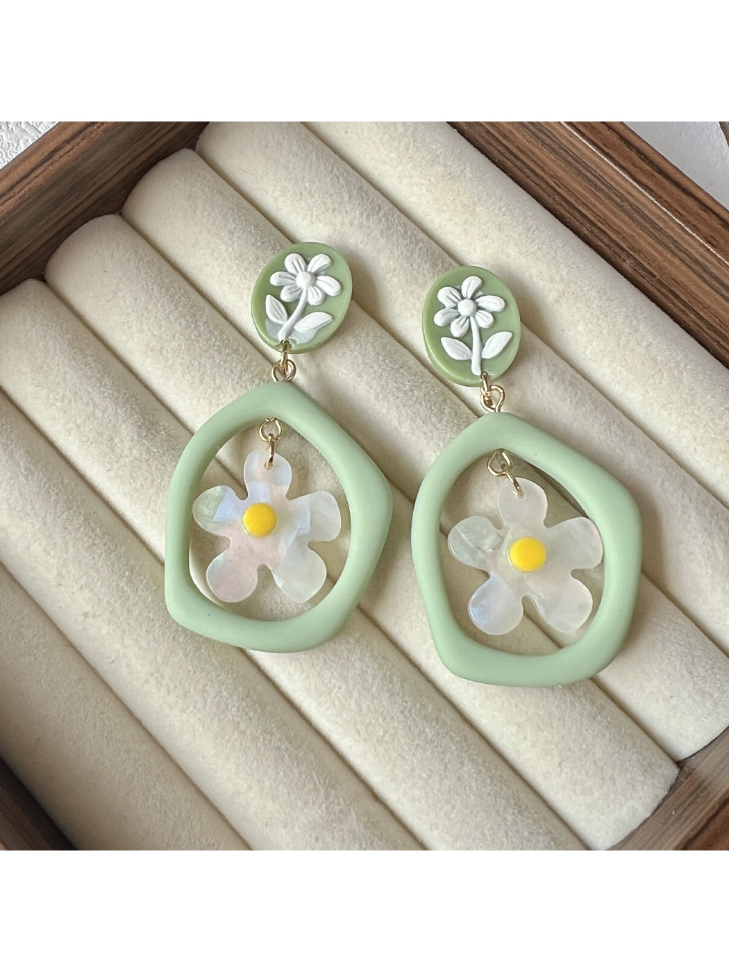 Pair of green daisy hoop earrings displayed on a white background