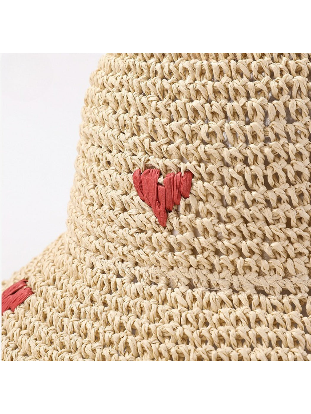 Model wearing the straw bucket hat with heart detail outdoors