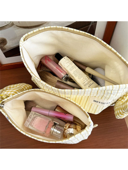 Striped cosmetic bag with plush charm hanging from a hook