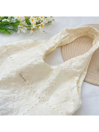 Side view of white floral embroidered hobo bag showing zipper and strap details