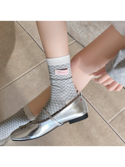 Model sitting cross-legged wearing Rufia crew socks with casual outfit