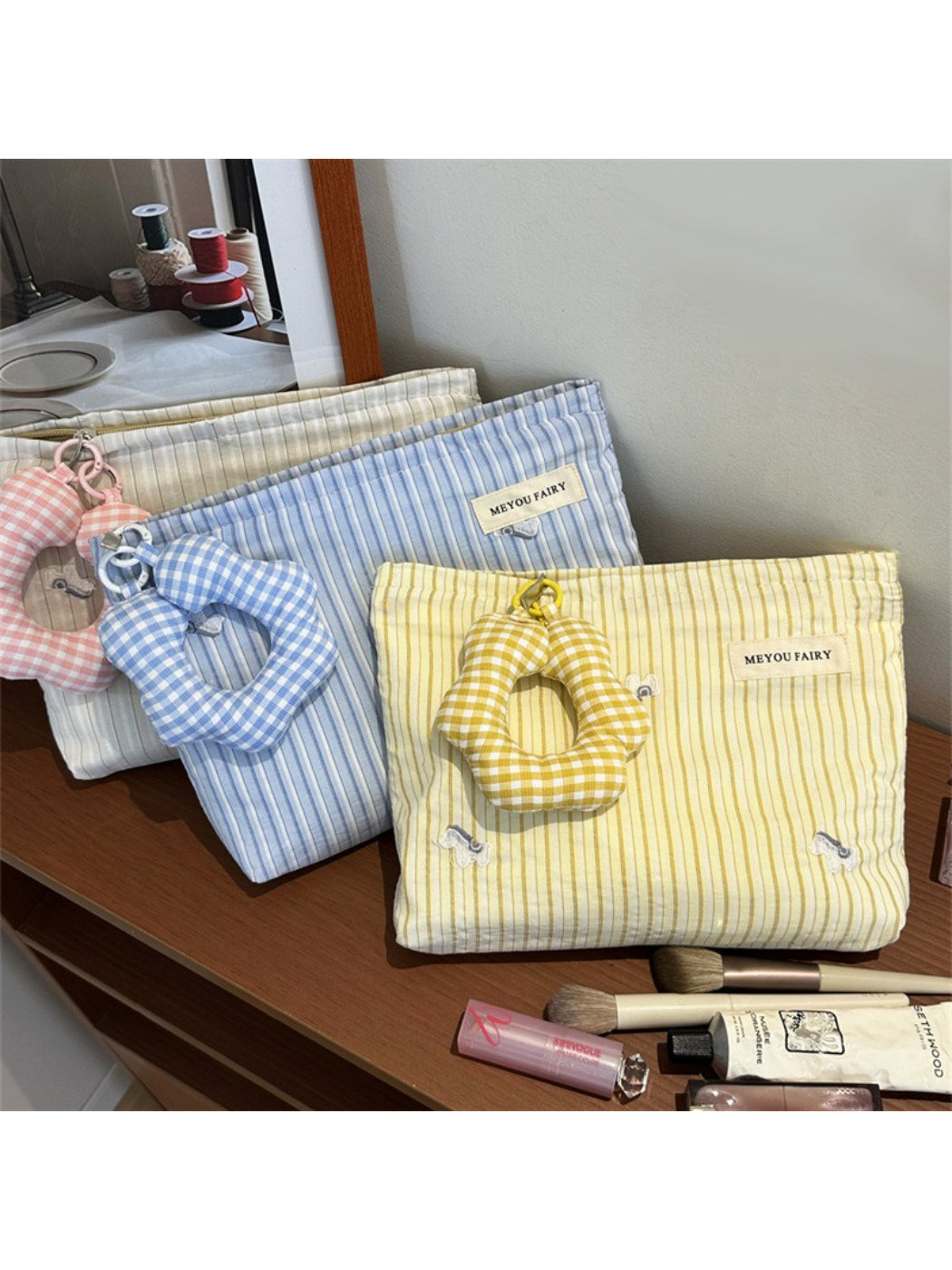 Close-up of striped cosmetic bag zipper and plush charm detail