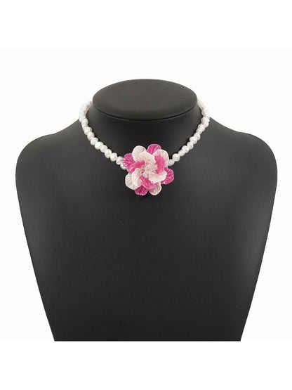 Close-up of flower pendant on white beaded necklace showing detailed bead arrangement