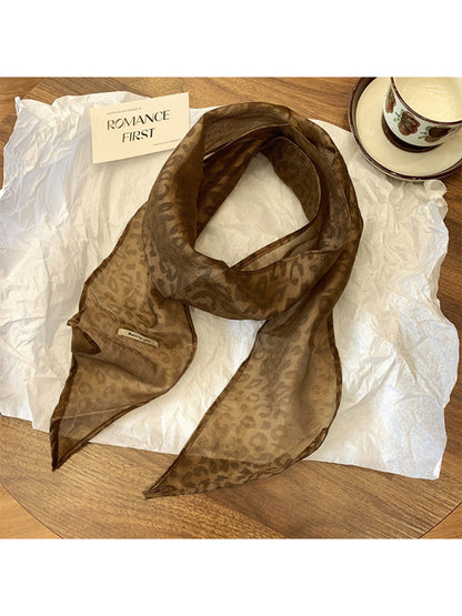 Leopard print neck scarf displayed with matching accessories on wooden surface