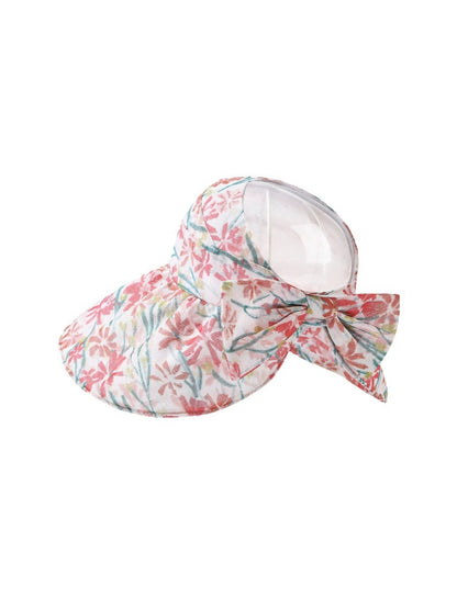 Model wearing pastel bloom wide brim hat outdoors with greenery background