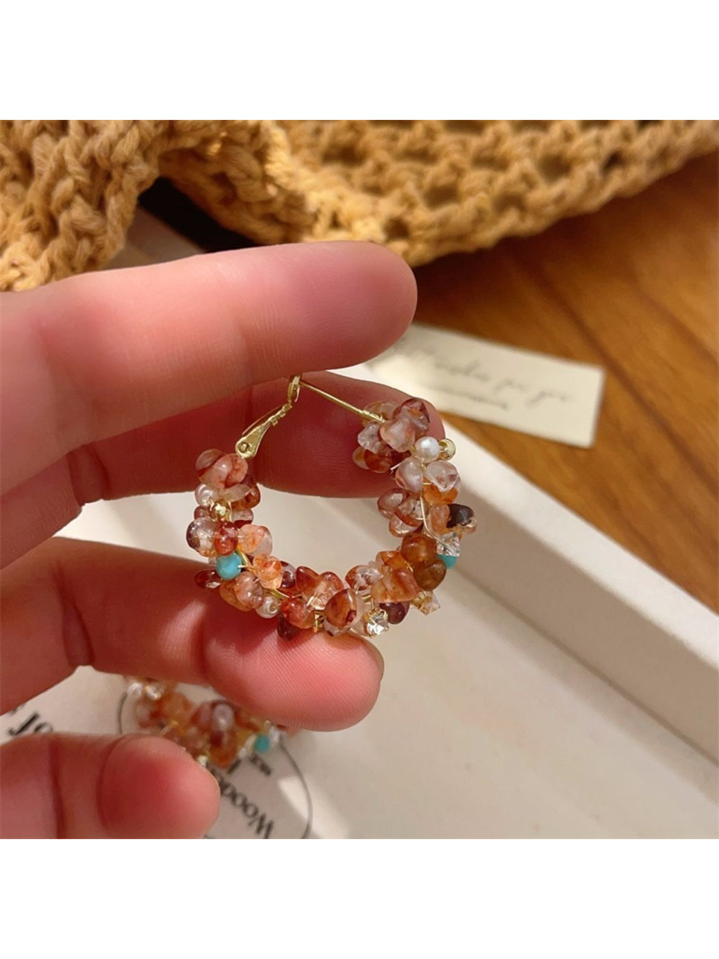 Pair of light tone floral hoop earrings laid flat on a textured surface