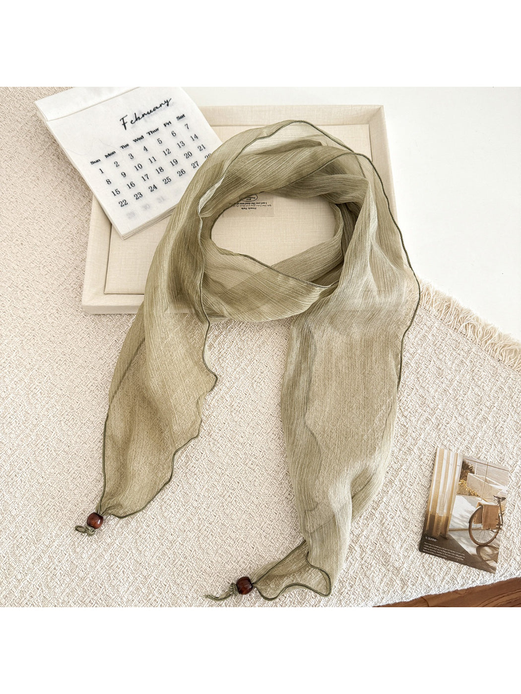 Soft pleated sheer skinny scarf folded neatly showing lightweight fabric