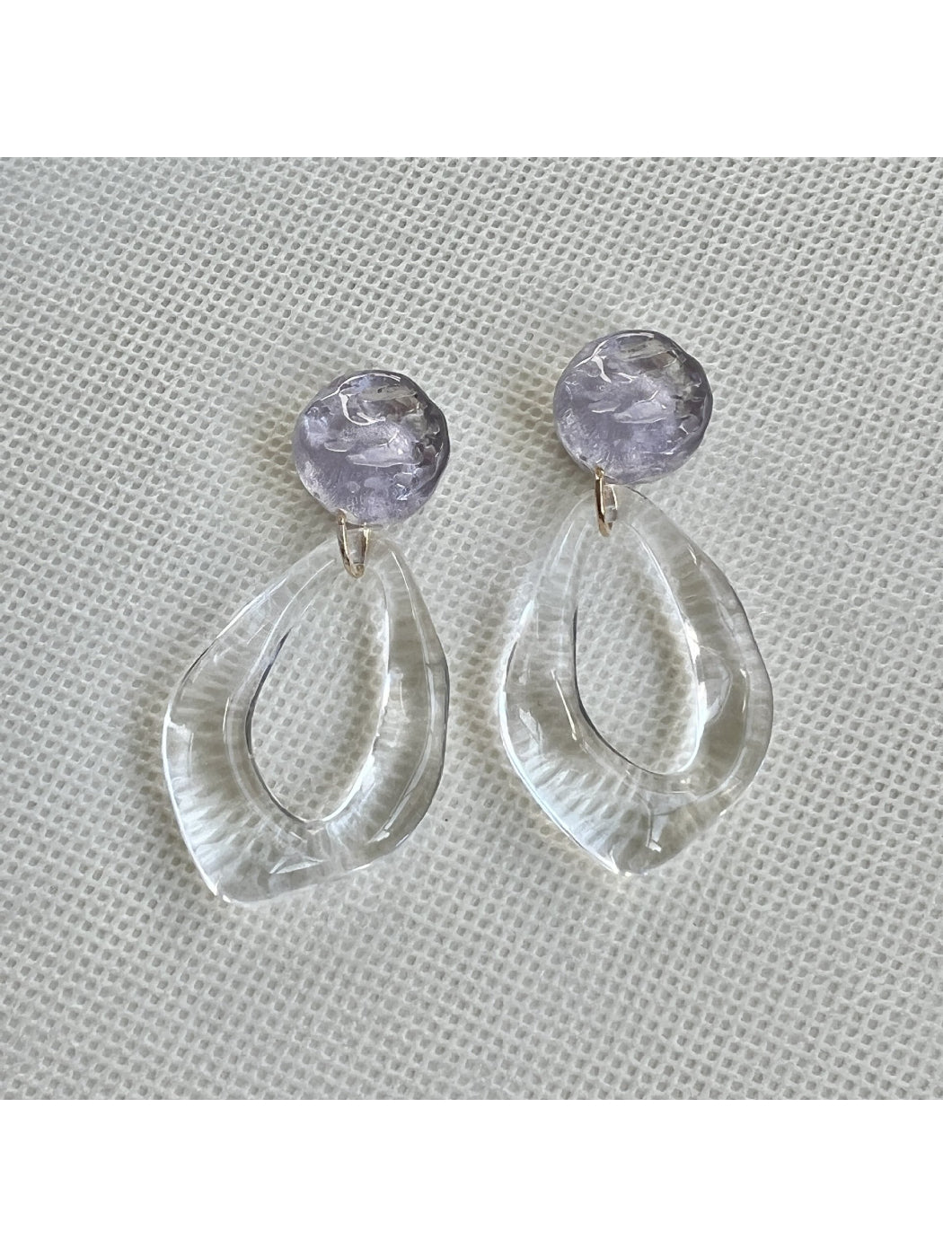 Close-up of Earwish clear teardrop hoop earrings on white background