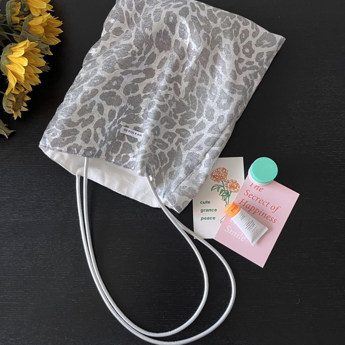 Side view of grey leopard print tote bag showing black strap detail