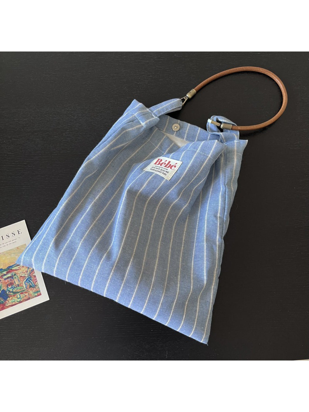 Side view of Cosbai blue stripe slouch shoulder bag highlighting its slouchy shape and stripes