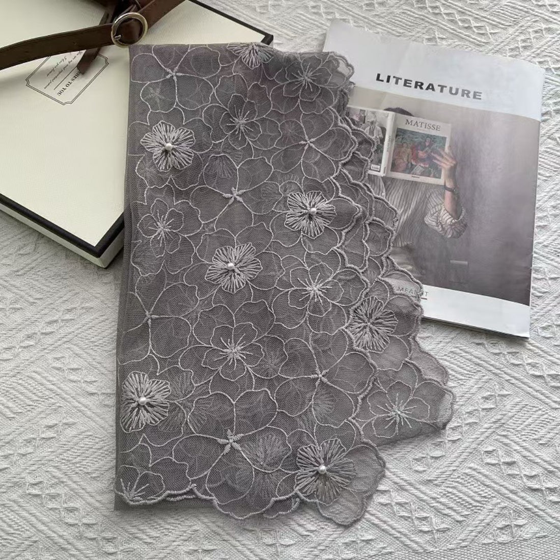 Detailed view of pearl trim along the edge of the floral lace scarf