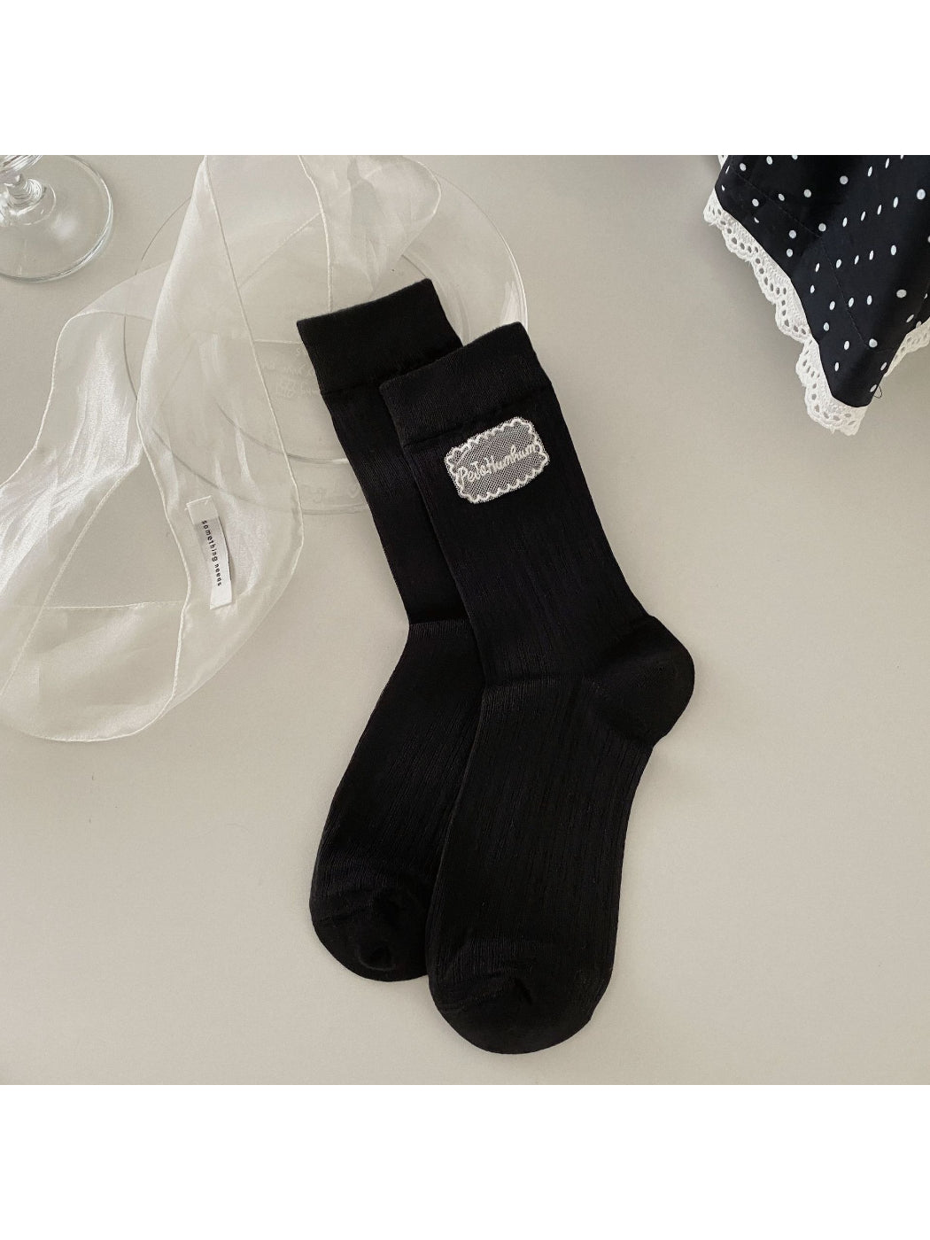 Rufia Sweet Label crew socks displayed on wooden surface with soft light