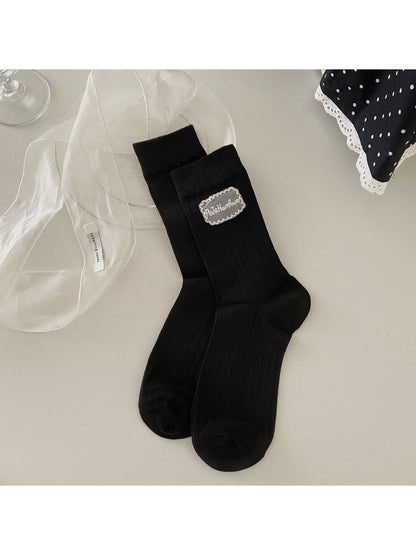 Rufia Sweet Label crew socks displayed on wooden surface with soft light