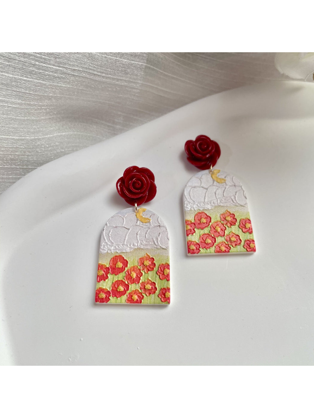Close-up of Earwish Rose Garden earrings showing detailed pink rose petals and gold hooks