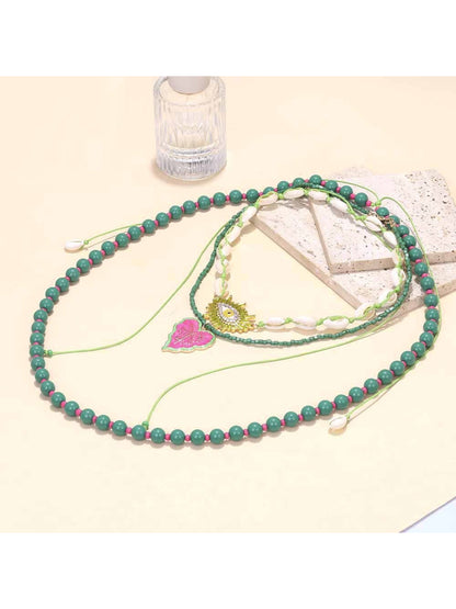 Neckit layered beaded necklace with leaf pendant displayed on a black surface