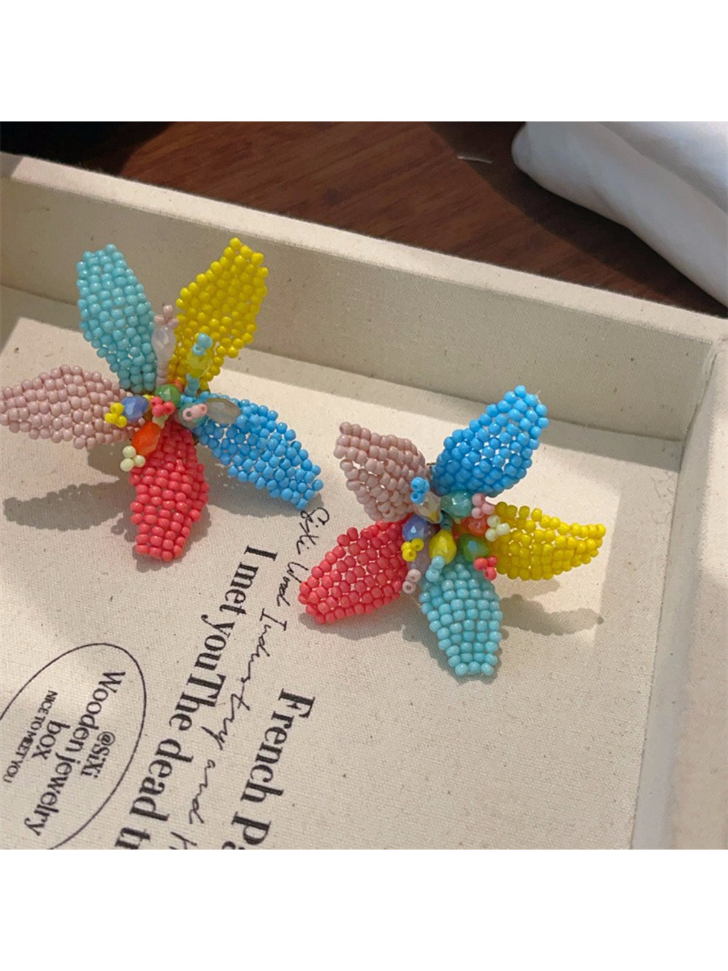 Pair of Earwish colorful beaded flower earrings displayed on a white background