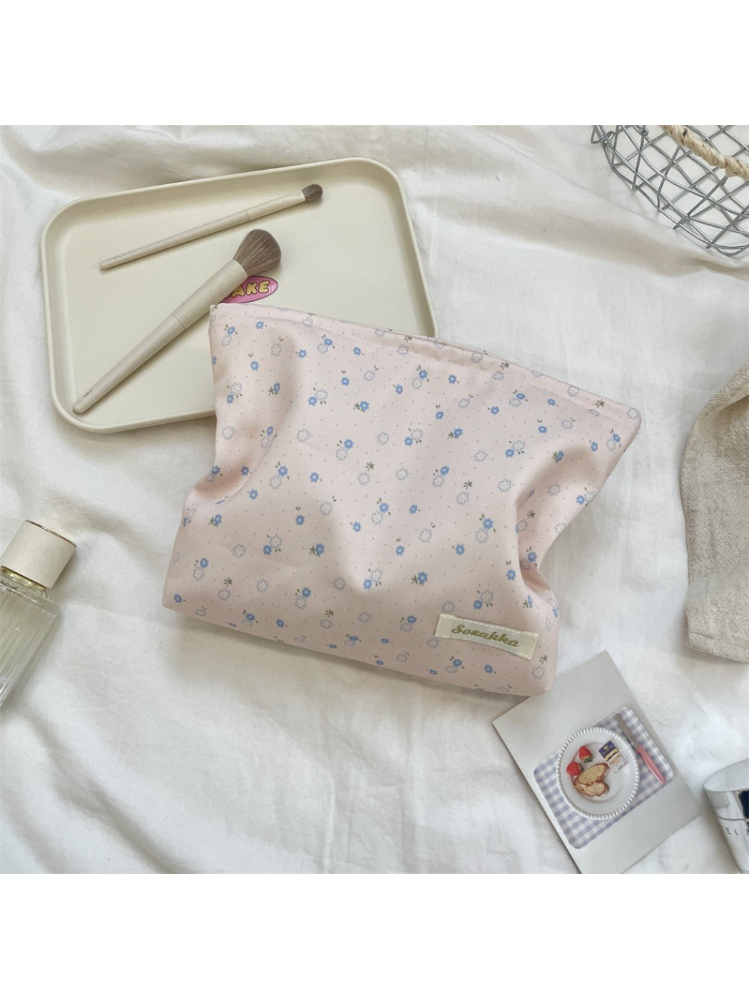 Cosbai cosmetic pouch with floral pattern next to makeup brushes and accessories