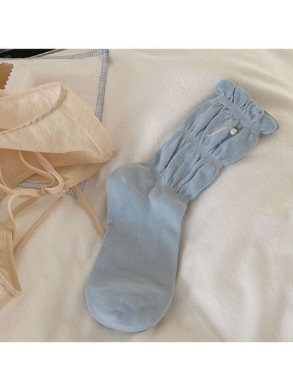 Flat lay of Rufia pastel pink crew socks with ruffle trim on white background