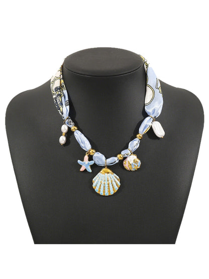 Neckit Botanical Charm fabric necklace with green leaves and flower charms on white fabric