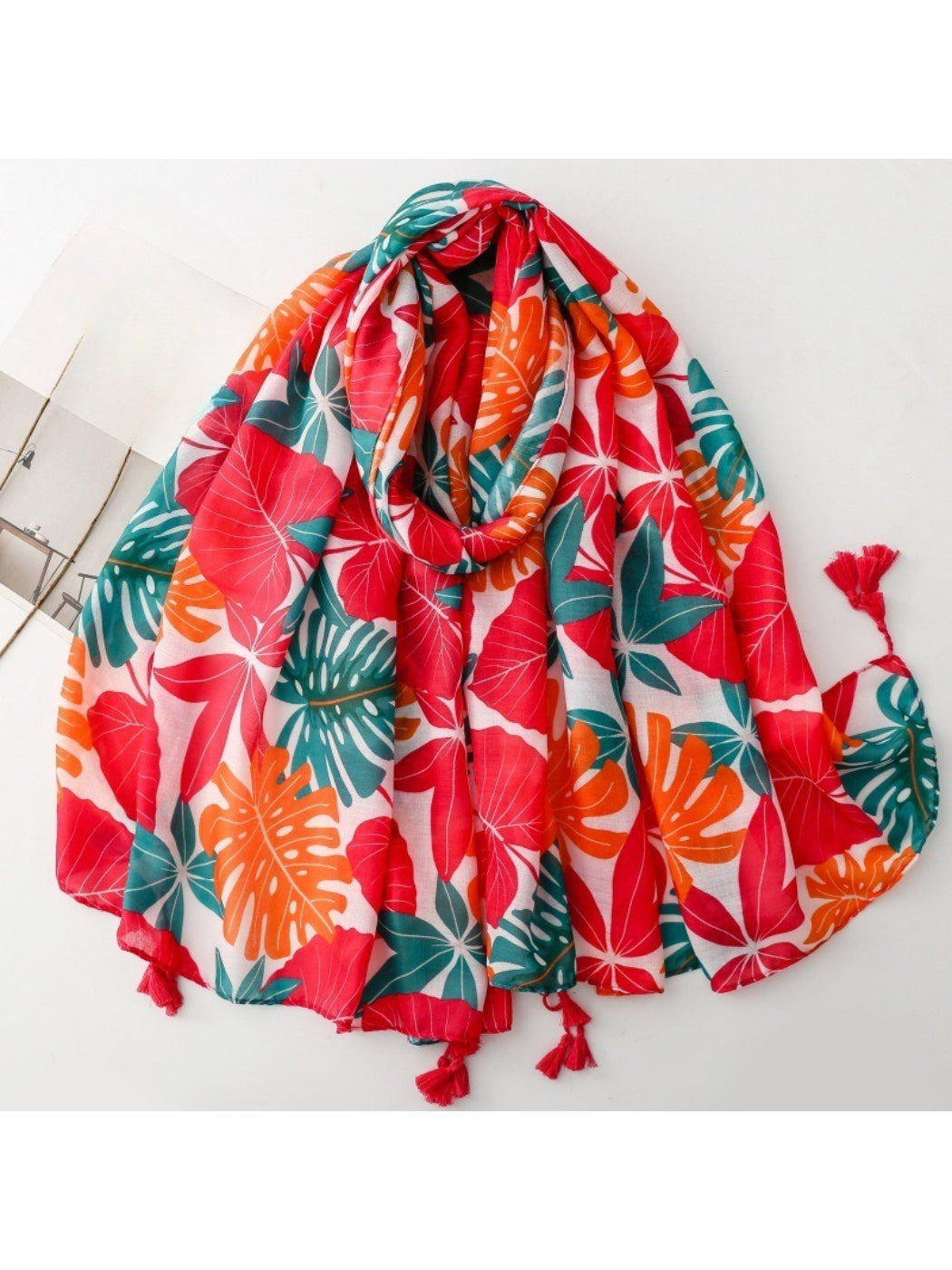 Scarvii bold botanical print scarf folded showing green and orange leaf patterns on white background