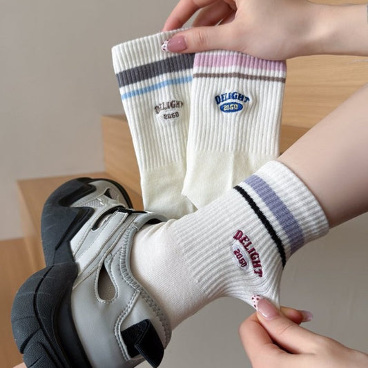 Pair of Rufia Retro Stripe Letter Crew Socks in white with colorful stripes and letter design