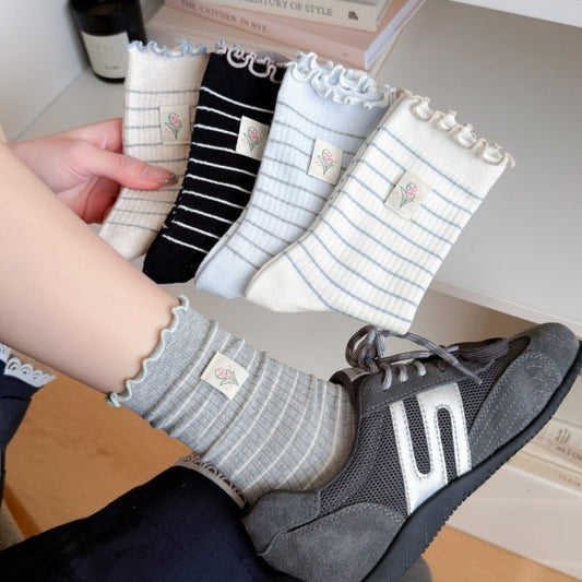 Pair of Rufia Lettuce Edge Stripe Crew Socks in white with black stripes laid flat