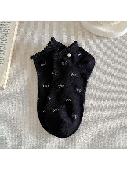 Pair of Rufia ankle socks laid flat displaying bow pattern and frill edges