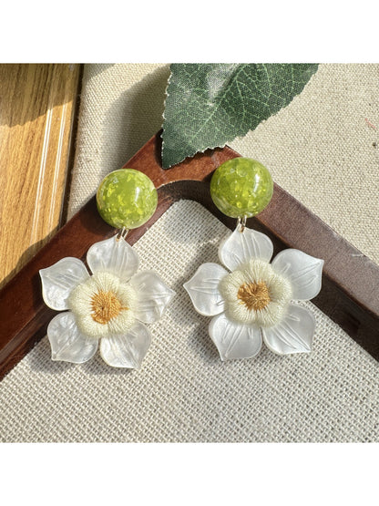 Close-up of Earwish white flower drop earrings with gold hooks on a white background