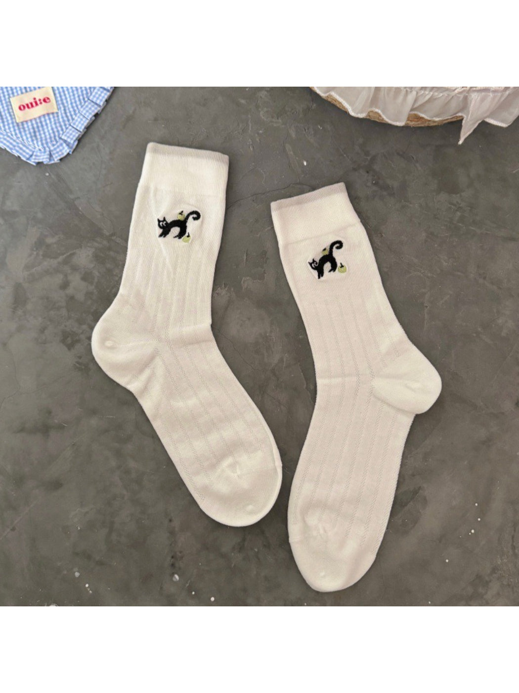 Rufia black cat crew socks paired with casual sneakers on wooden floor