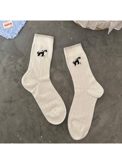 Rufia black cat crew socks paired with casual sneakers on wooden floor