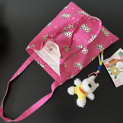 Model carrying the pink puppy print tote bag over shoulder outdoors