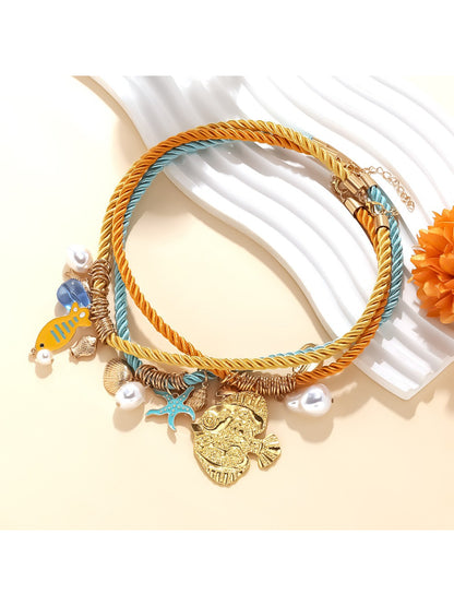 Ocean Charm rope necklace with shell details displayed coiled on a neutral surface