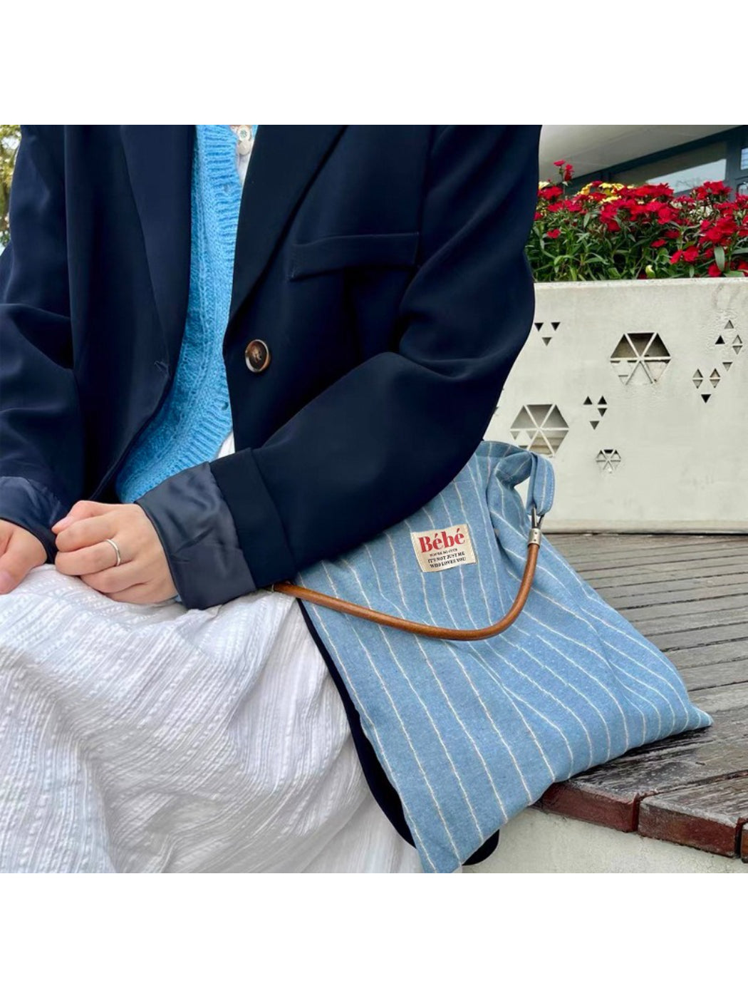 Cosbai blue stripe slouch shoulder bag hanging on a hook with a white background