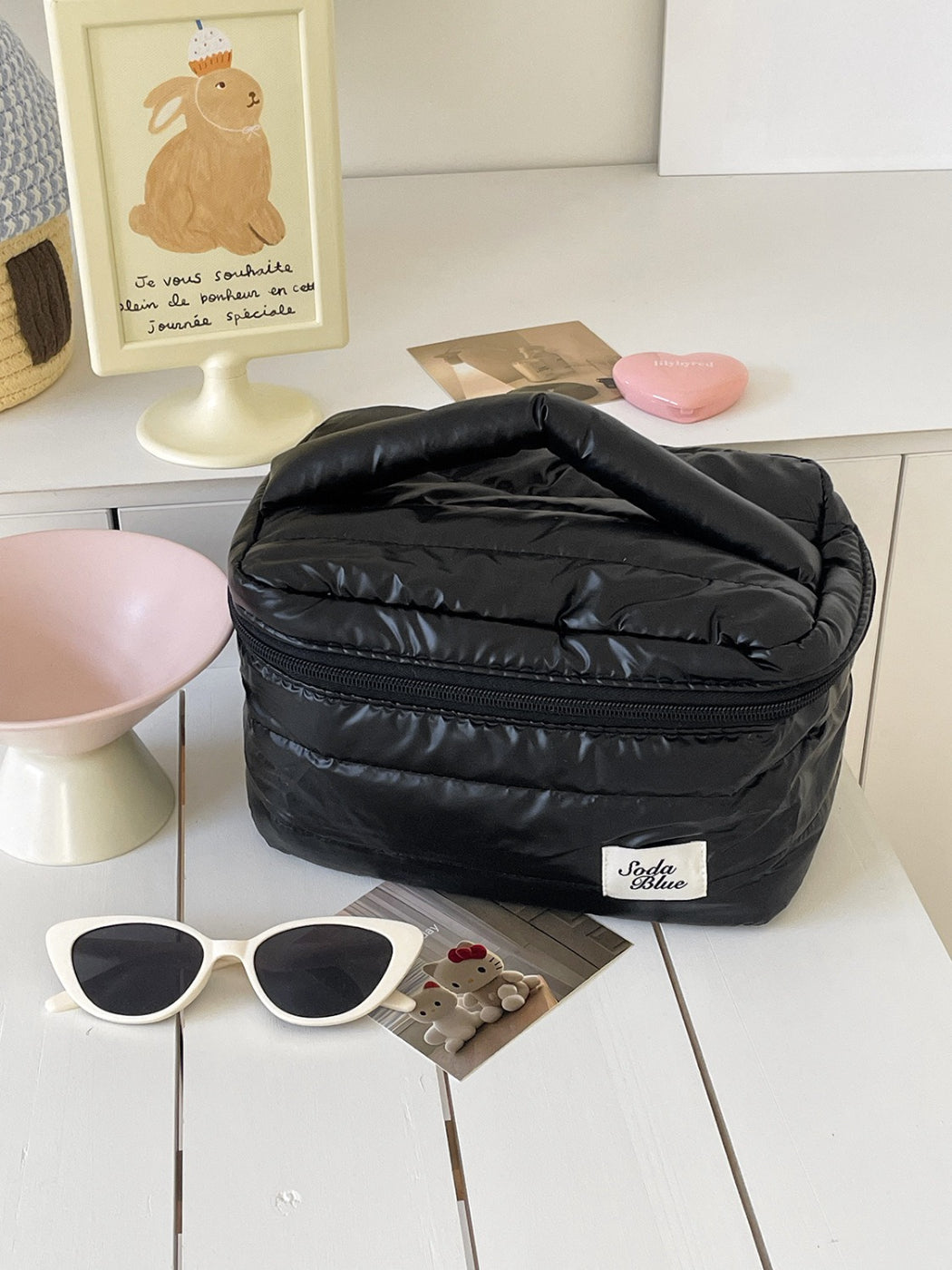 Side view of beige quilted puffy makeup bag with handle